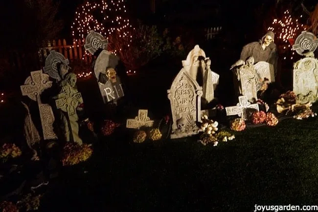 A front yard spooky halloween graveyard scene with tombstones, ghouls, skeketons, & much more at night.