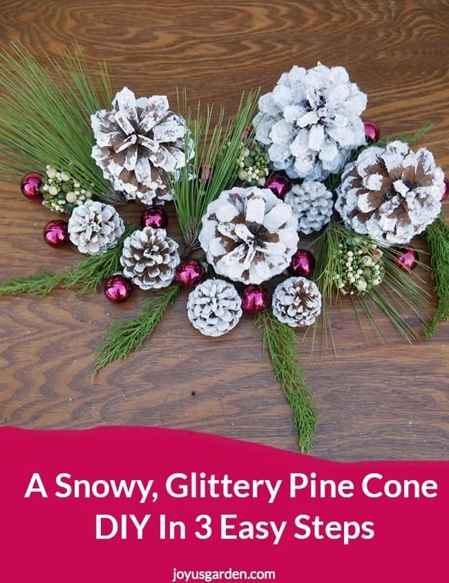 white glittered pine cones sit on a table decorated with glass balls & evergreen branches the text reads A Snowy, Glittery Pine Cone DIY In 3 Easy Steps