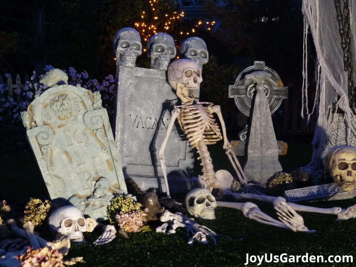 A snippet of a halloween graveyard scene diy lit at night with skeletons, skulls, & tombstones.