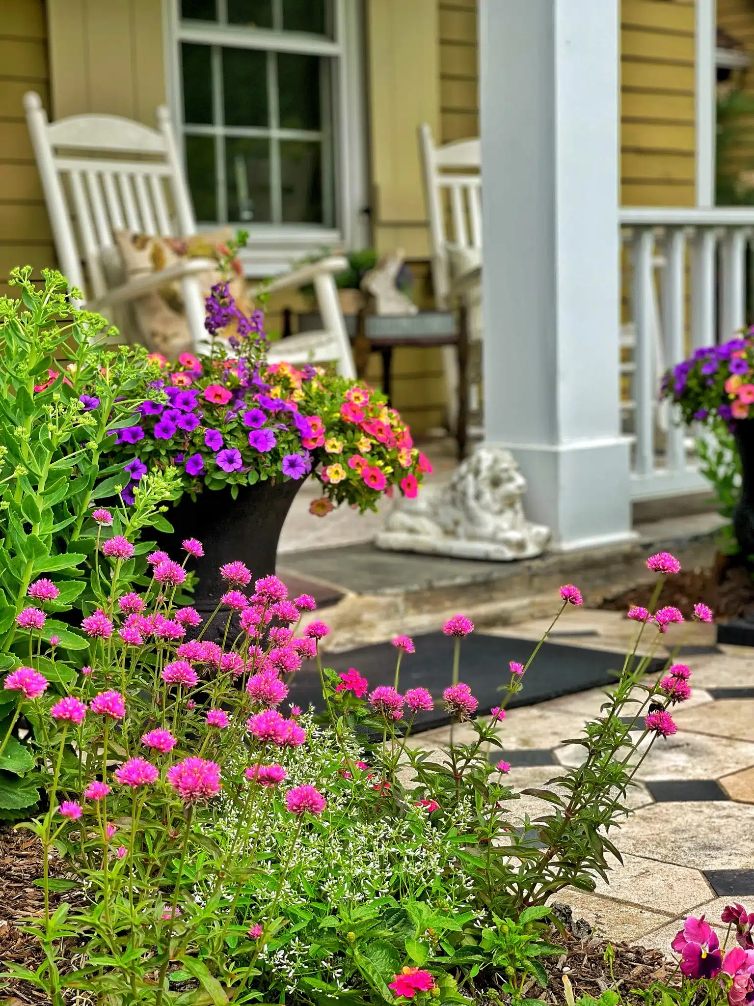 colorful petunias displayed in an urn next to a front porch