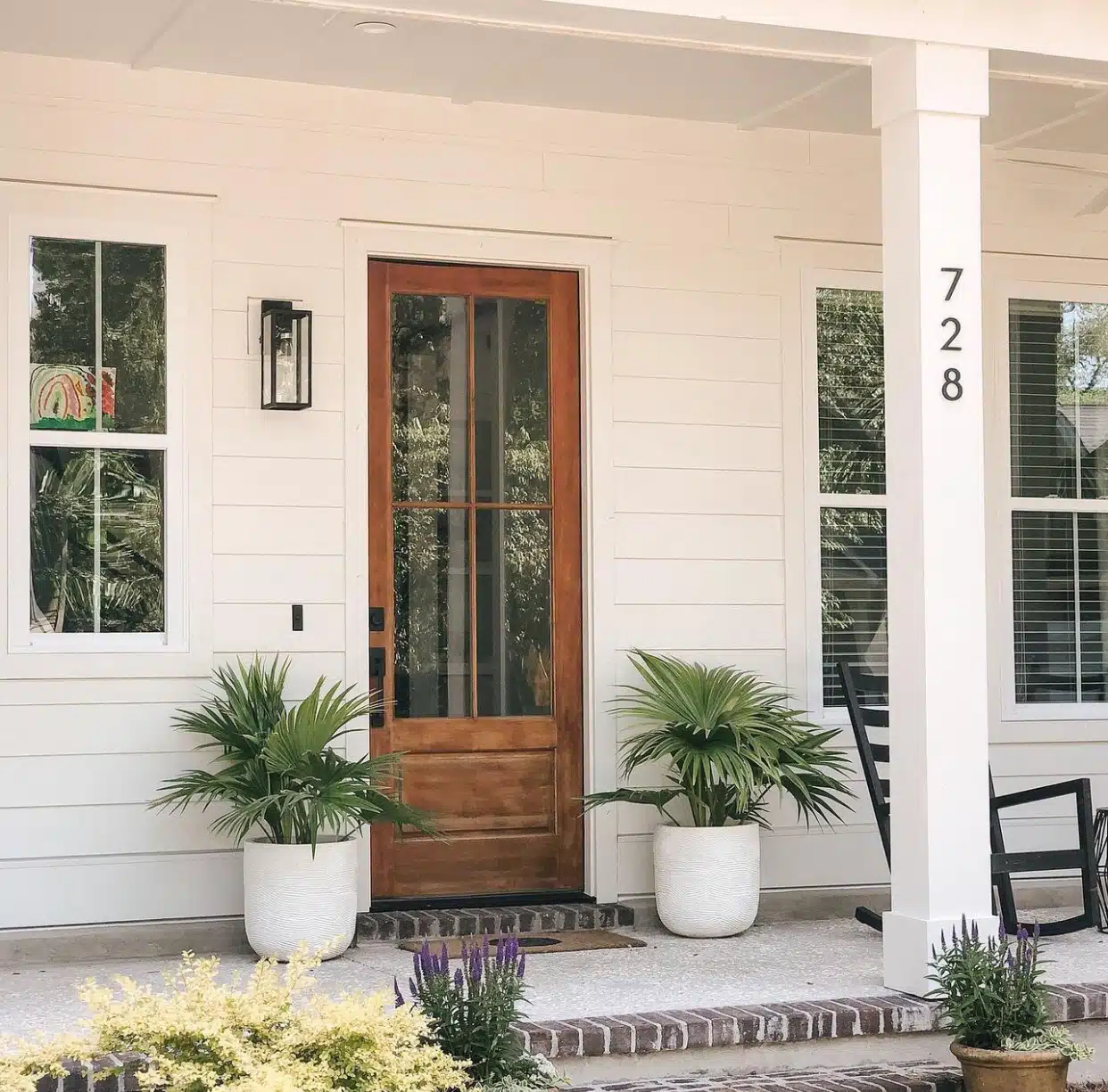 two palms in ceramic planters on a front porch