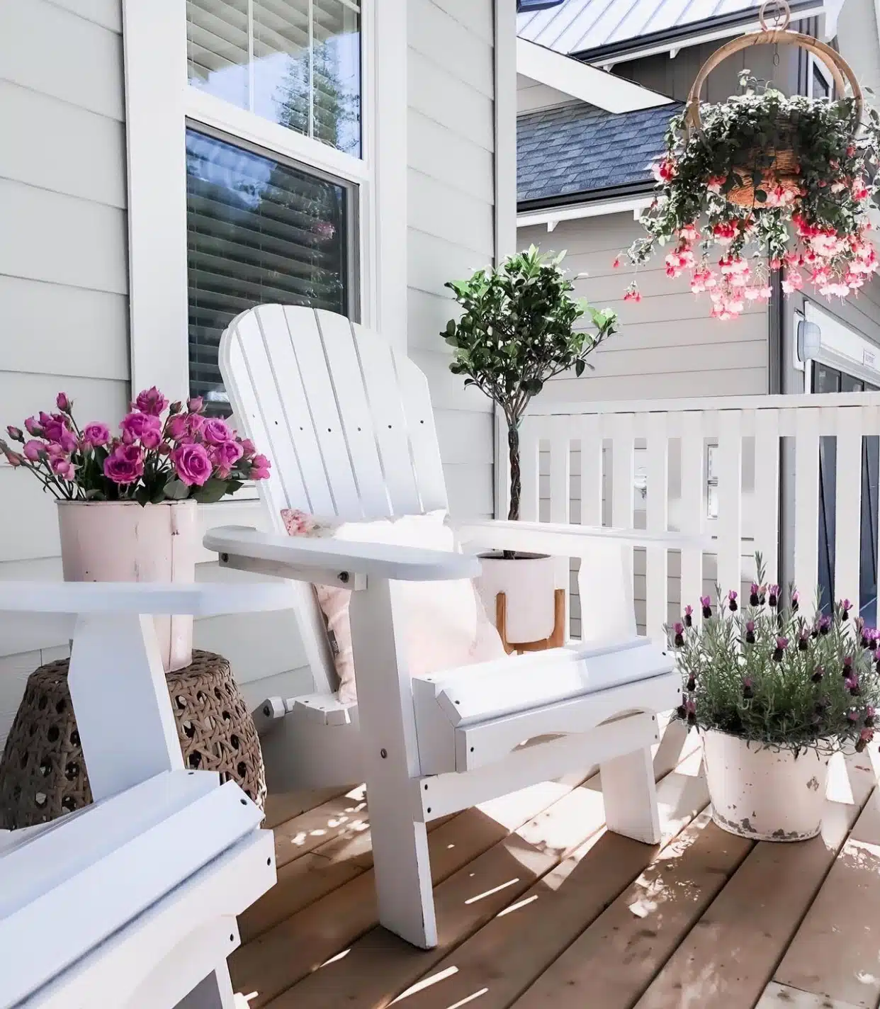 two outdoor chairs on front porch with a braid topiary and roses